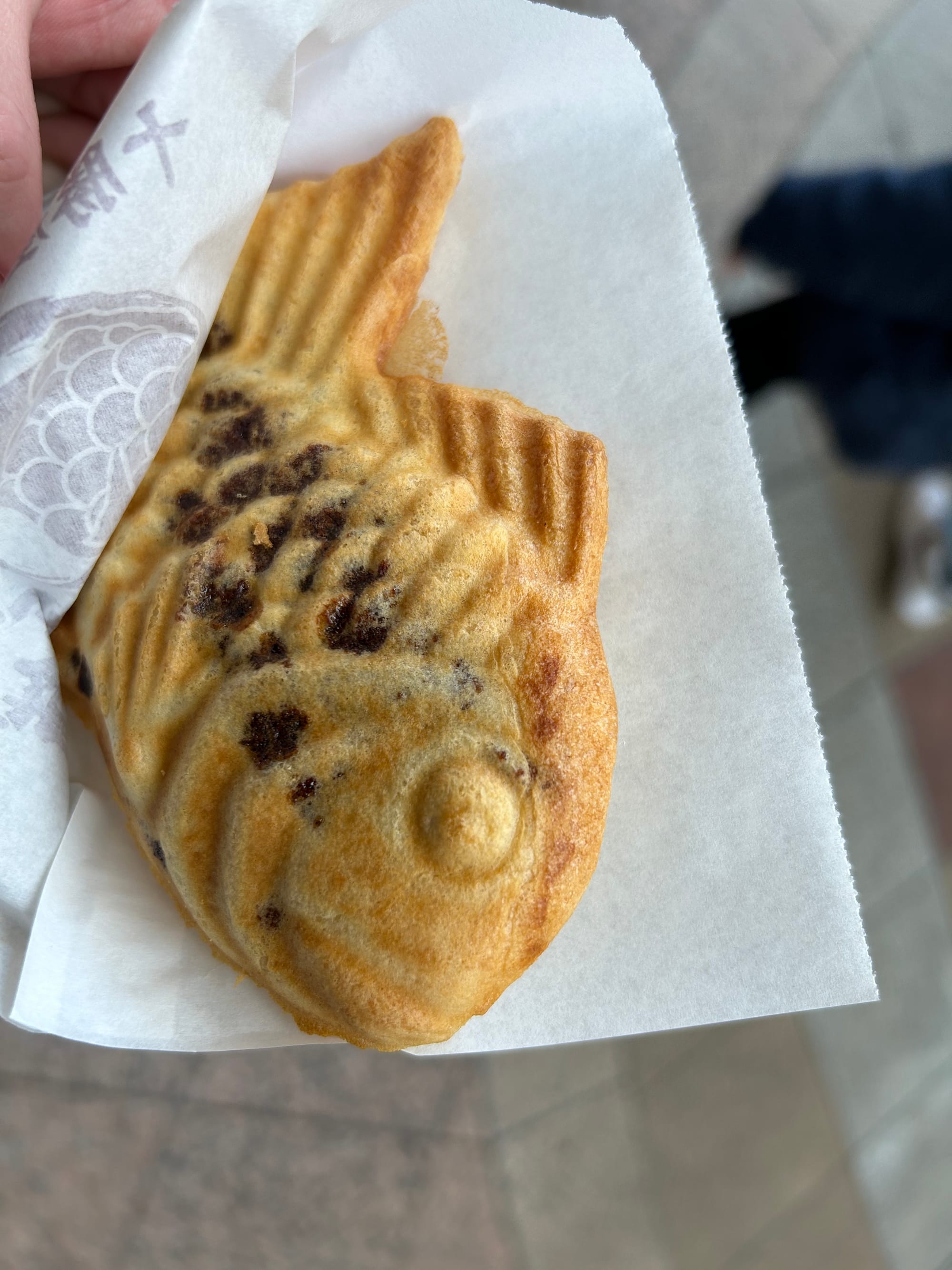 A fresh taiyaki in served on a piece of paper.