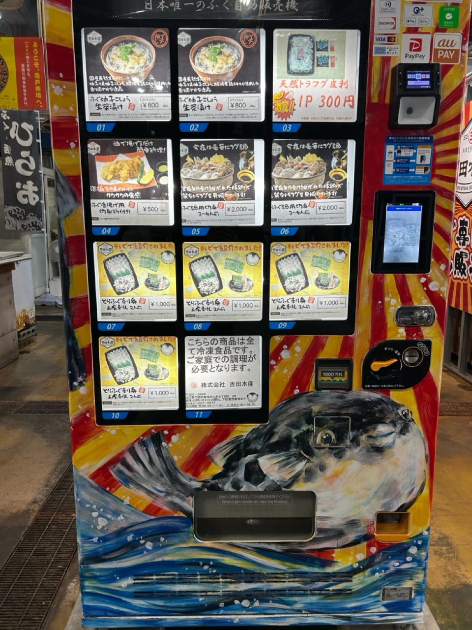 Sushi vending machine with a painting  of a pufferfish hovering above the water.